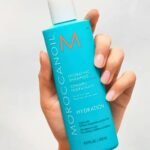 Botella del champú hidratante Moroccanoil con aceite de argán en una mano