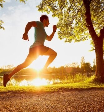 Hombre corriendo al aire libre al amanecer junto a un lago