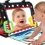 bebé jugando durante tummy time con libro sensorial montessori y espejo plegable.