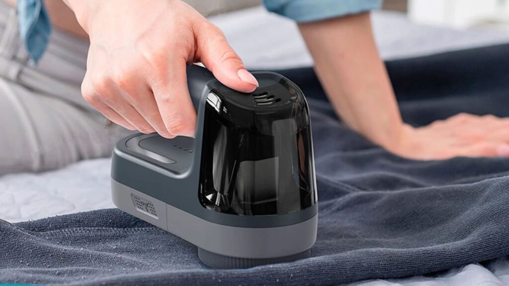 Mano usando un quitapelusas eléctrico en jersey de invierno