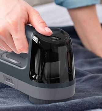 Mano usando un quitapelusas eléctrico en jersey de invierno