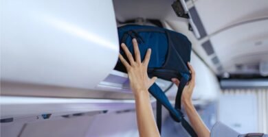Los 3 modelos de mochilas de cabina más vendidos que te evitan pagar por facturar maletas 4 Persona guardando mochila de cabina en avión para viajar sin facturar equipaje