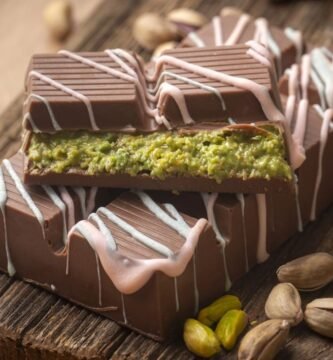 El chocolate Dubai arrasa internet: qué tiene y por qué todo el mundo está obsesionado con él 1 Chocolate Dubai relleno de pistacho con cobertura de chocolate y decoración blanca sobre tabla de madera