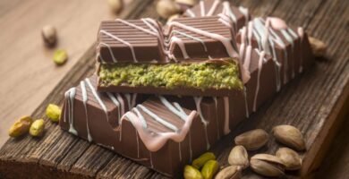 Chocolate Dubai relleno de pistacho con cobertura de chocolate y decoración blanca sobre tabla de madera