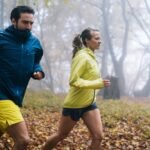 Dos corredores entrenan en un bosque con cortavientos para protegerse del frío, el viento y la lluvia